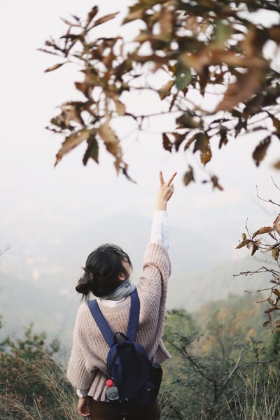 妇女与和平标志提高右手面临山
